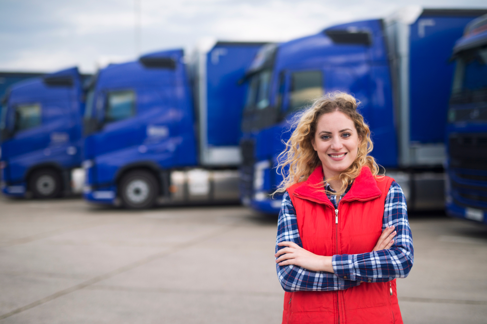 Woman truck driver standing in front of blue trucks